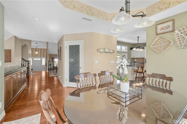 dining area with baseboards, stairs, visible vents, and wood finished floors