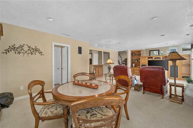 dining room with recessed lighting, light colored carpet, a textured ceiling, and baseboards