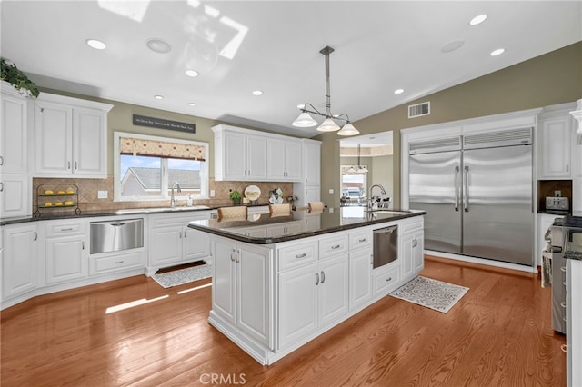 kitchen featuring a kitchen island, visible vents, white cabinets, a warming drawer, and high end appliances