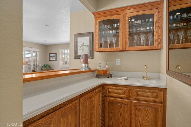 bar with a textured ceiling, indoor wet bar, and a sink