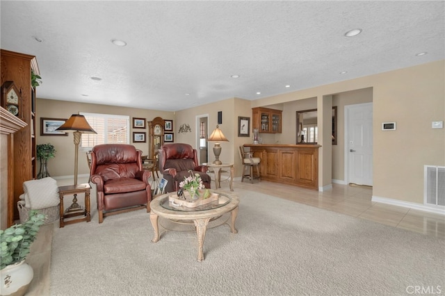 living room featuring light carpet, light tile patterned floors, a textured ceiling, and visible vents