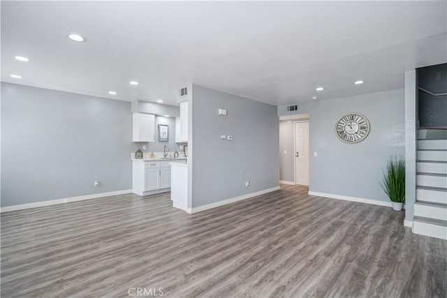 unfurnished living room featuring recessed lighting, a sink, baseboards, and wood finished floors