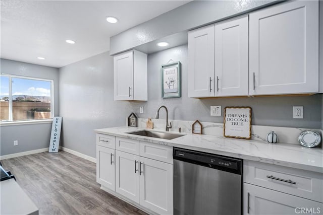 kitchen with baseboards, white cabinets, light wood-type flooring, stainless steel dishwasher, and a sink