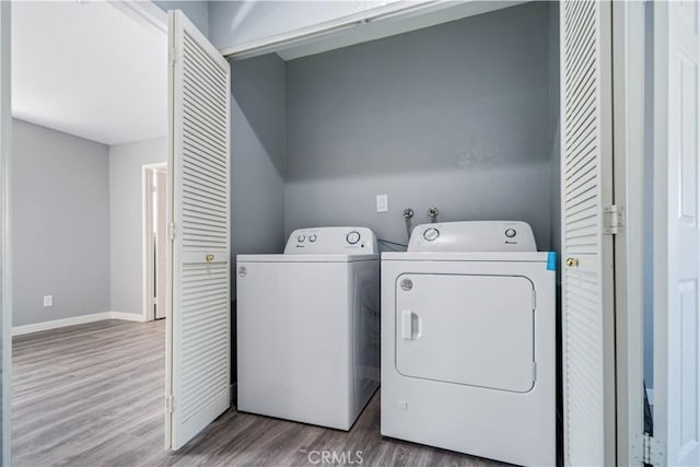 laundry room with laundry area, separate washer and dryer, wood finished floors, and baseboards