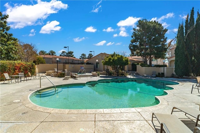 community pool with a patio and fence