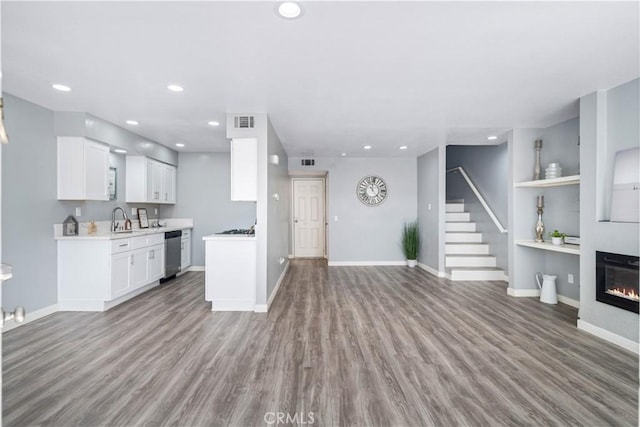 kitchen featuring visible vents, dishwasher, a glass covered fireplace, open floor plan, and light countertops