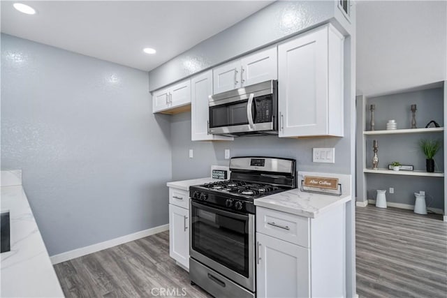 kitchen with baseboards, white cabinetry, stainless steel appliances, and wood finished floors