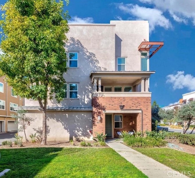 view of front of house featuring a front yard, brick siding, and stucco siding