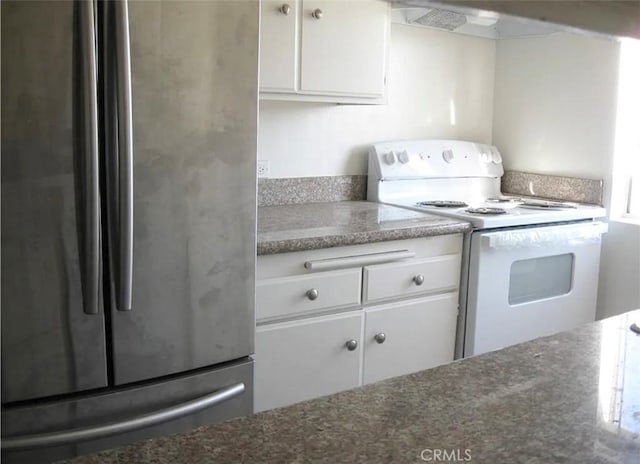 kitchen with freestanding refrigerator, white cabinets, and white electric stove