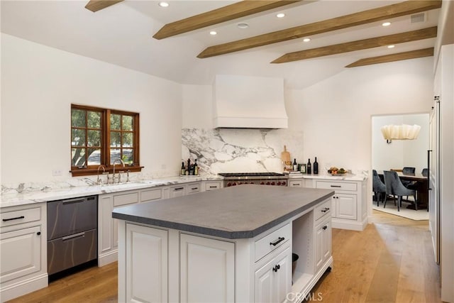 kitchen featuring white cabinets, a kitchen island, light wood-type flooring, premium range hood, and beam ceiling