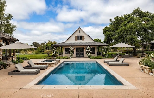 outdoor pool with a patio, an outdoor structure, an exterior structure, and an in ground hot tub