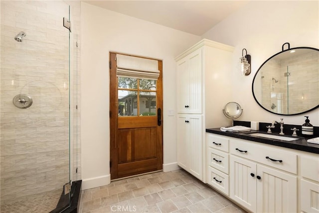 bathroom featuring a stall shower, vanity, and baseboards