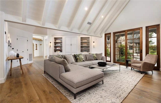 living room featuring beam ceiling, visible vents, light wood-style floors, high vaulted ceiling, and baseboards