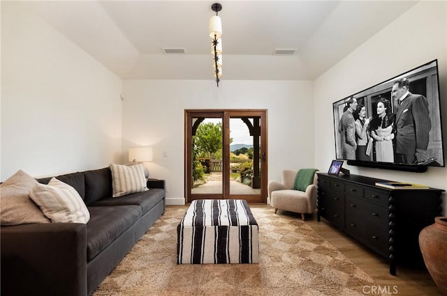 living area with light wood-style flooring, visible vents, and a tray ceiling