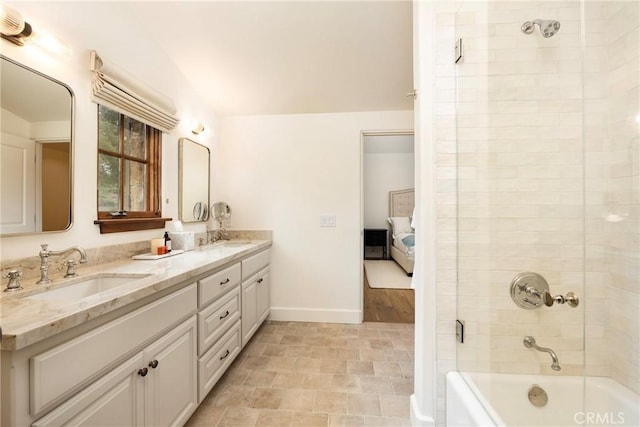 bathroom featuring connected bathroom, a sink, baseboards, and double vanity