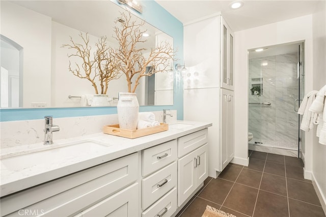 bathroom featuring double vanity, a stall shower, a sink, and toilet