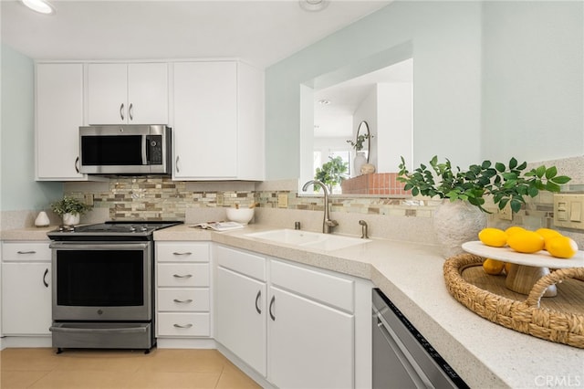 kitchen featuring stainless steel appliances, light countertops, a sink, and decorative backsplash