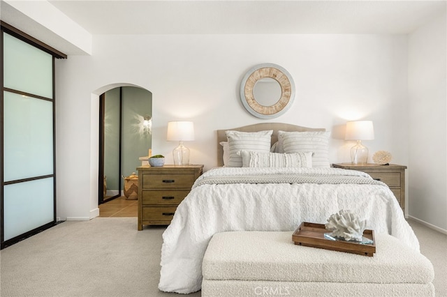 bedroom featuring carpet, arched walkways, and baseboards