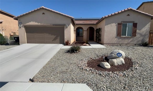 mediterranean / spanish-style home with solar panels, concrete driveway, an attached garage, and stucco siding