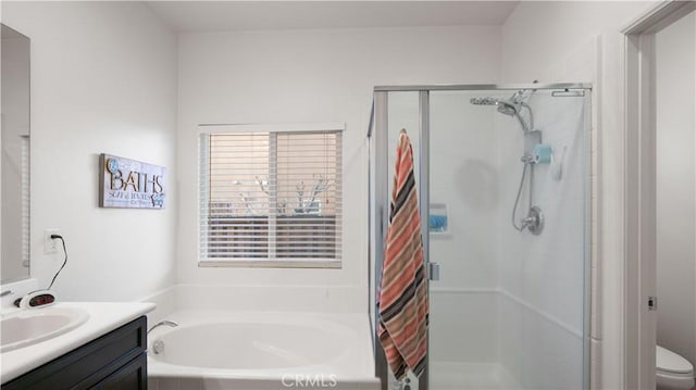 full bathroom featuring toilet, a stall shower, a bath, and vanity