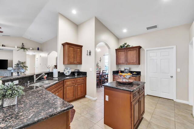 17717 Bangor Ave, Hesperia, CA 92345 - kitchen with arched walkways, a sink, vaulted ceiling, open floor plan, and dark stone counters