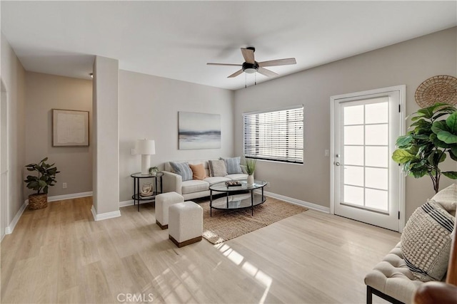 living area featuring ceiling fan, light wood finished floors, and baseboards