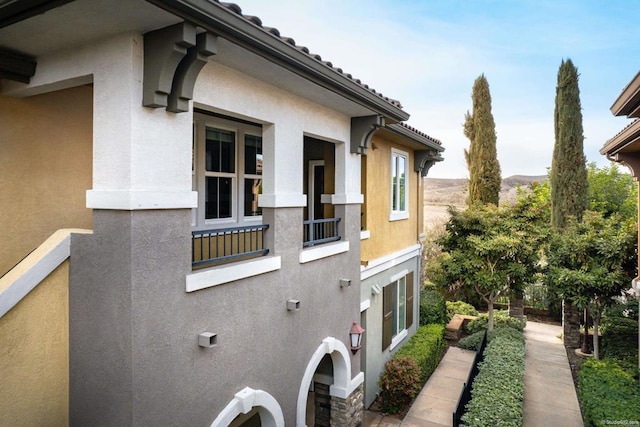 view of side of home with a tile roof and stucco siding