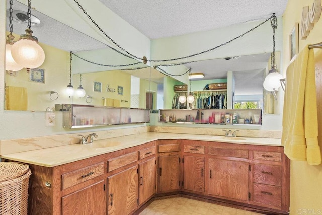 full bathroom featuring double vanity, a sink, a textured ceiling, and tile patterned floors