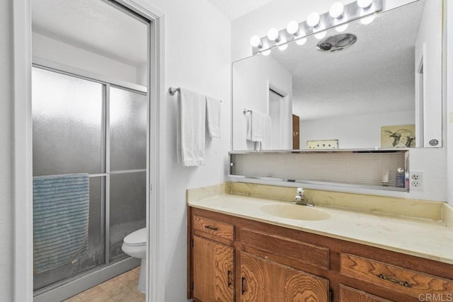 bathroom with toilet, a stall shower, a textured ceiling, and vanity