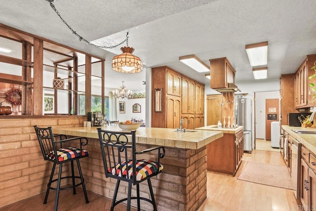 kitchen with stainless steel appliances, light wood finished floors, a sink, and light countertops