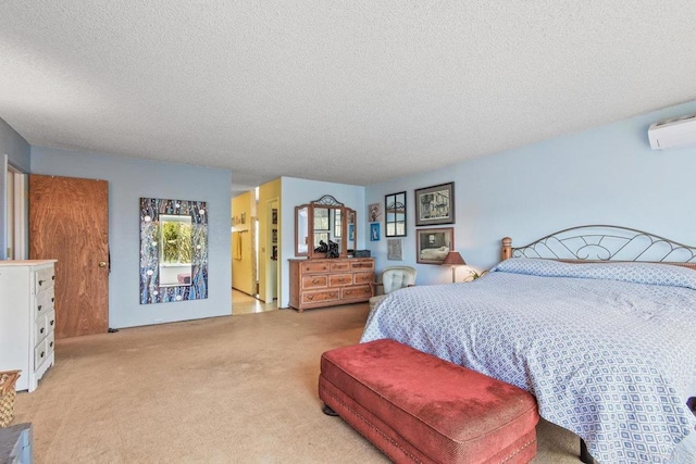 bedroom featuring light colored carpet, a wall unit AC, and a textured ceiling