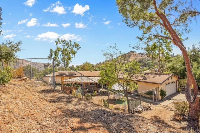 back of house with a detached garage, fence, a mountain view, and stucco siding