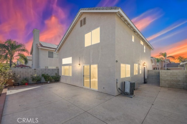 rear view of house featuring stucco siding, a fenced backyard, and a patio area