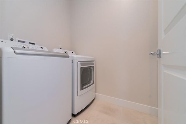 washroom with laundry area, independent washer and dryer, light tile patterned flooring, and baseboards