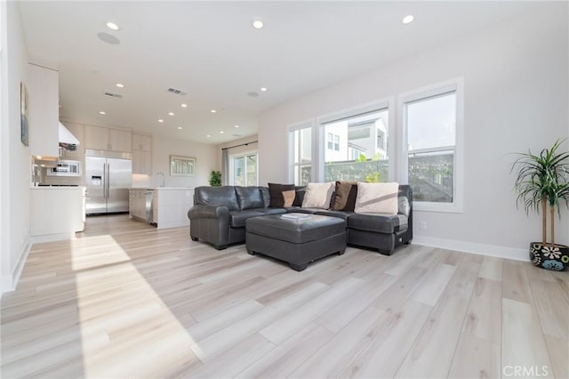 living room with visible vents, baseboards, light wood-style flooring, and recessed lighting