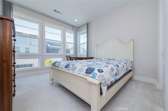 bedroom with light carpet, visible vents, baseboards, and multiple windows