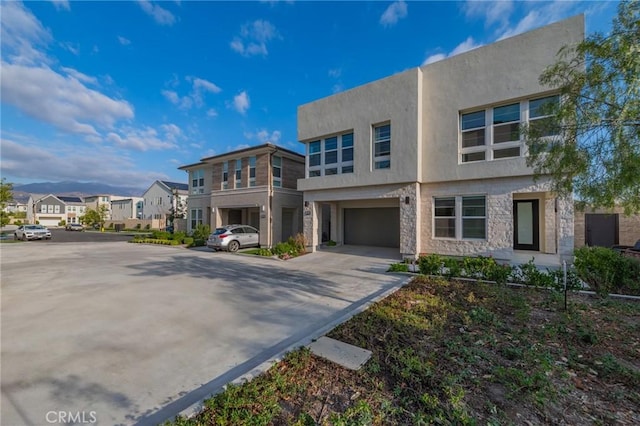 view of front facade with stucco siding, a garage, a residential view, stone siding, and driveway