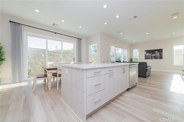 kitchen with a kitchen island with sink, modern cabinets, visible vents, and dishwasher