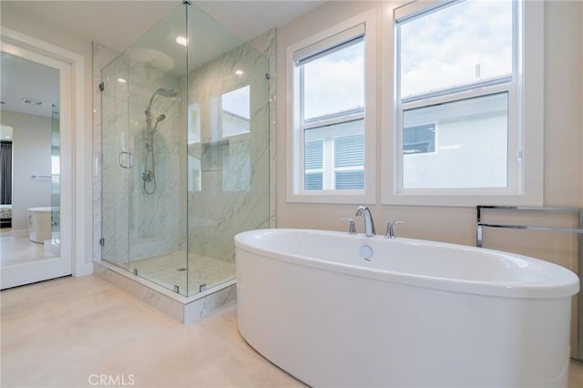 bathroom featuring a freestanding bath and a marble finish shower