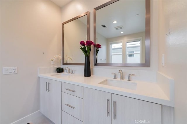 bathroom featuring double vanity, a sink, visible vents, and baseboards