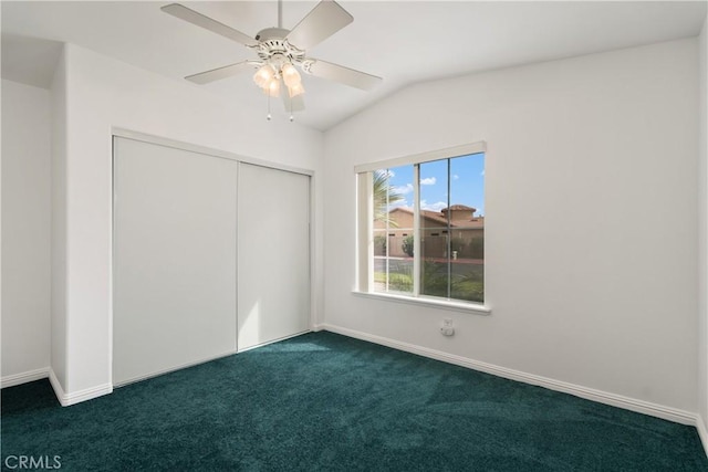 unfurnished bedroom with a closet, lofted ceiling, baseboards, and dark carpet