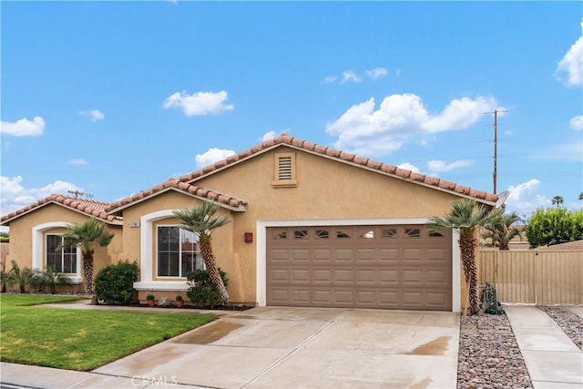 mediterranean / spanish house with stucco siding, a front lawn, driveway, fence, and a garage