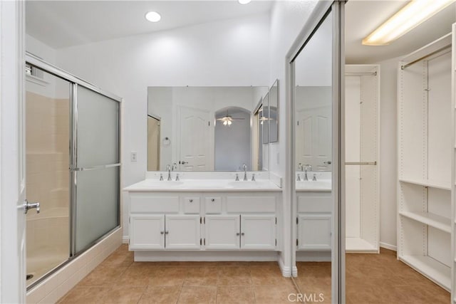 bathroom featuring a stall shower, a ceiling fan, a sink, tile patterned flooring, and double vanity