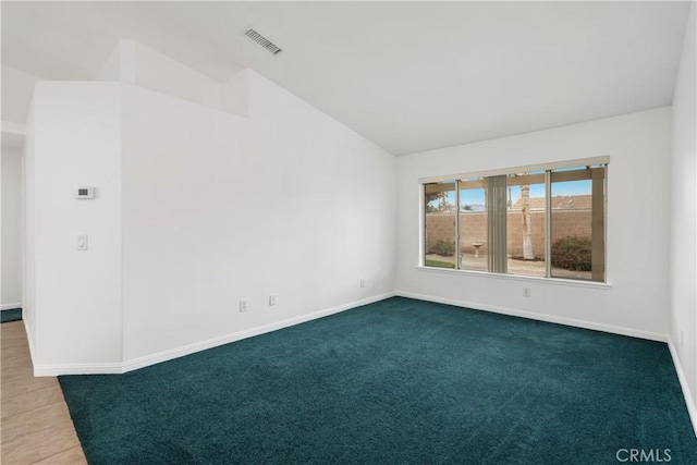 carpeted empty room featuring vaulted ceiling, baseboards, and visible vents