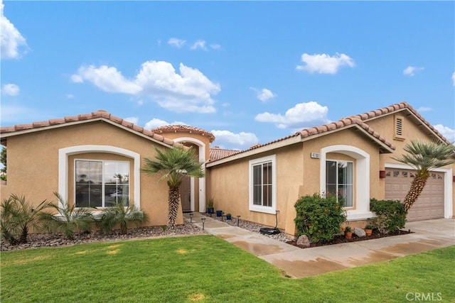 mediterranean / spanish home with stucco siding, a tiled roof, a front yard, and a garage