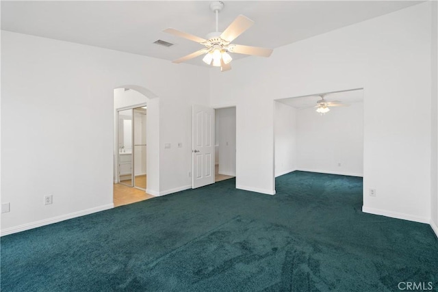 spare room featuring visible vents, arched walkways, baseboards, and carpet flooring