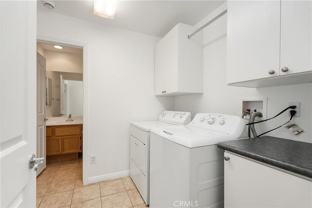 washroom featuring a sink, cabinet space, separate washer and dryer, light tile patterned floors, and baseboards