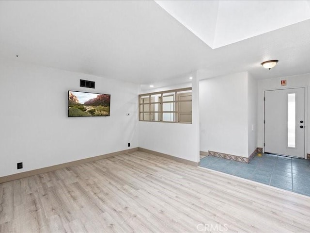 empty room featuring wood finished floors, visible vents, and baseboards