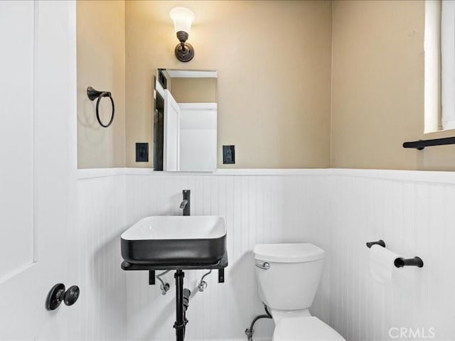 bathroom with a wainscoted wall, a sink, and toilet