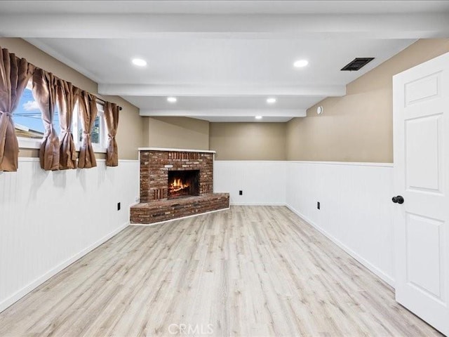unfurnished living room featuring a wainscoted wall, beamed ceiling, visible vents, and wood finished floors